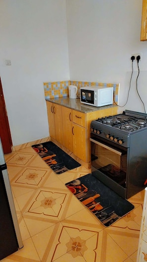 Uma cozinha compacta com fogão a gás, micro-ondas e armários de madeira.