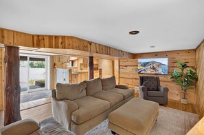 A wooden interior with a sofa, armchair, and a television mounted on the wall. - Lake Cabin on ATV Trails with Spacious Home with New Sauna! (Gordon)