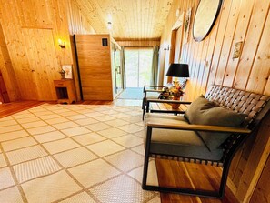 A wooden interior with a sofa, a lamp, and a view through a door. - Crystal Lake Retreat: Private Dock, Sauna, Parking, Firepit & 4BR (Gordon)