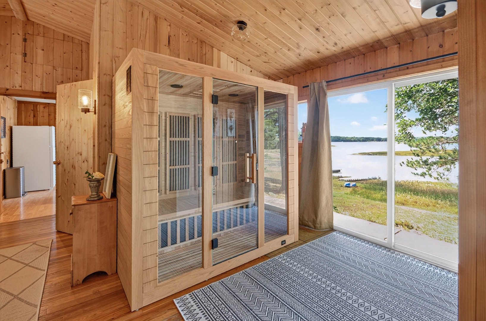 Un intérieur en bois avec une porte coulissante en verre donnant sur une vue sur un lac.