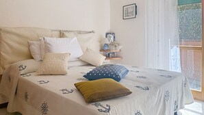 Een bed met een sprei met nautisch thema, een hoofdbord en meerdere kussens.