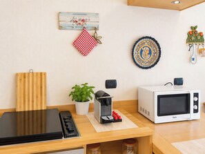 A kitchen with a stove, microwave, and a small coffee maker. - Coniglio Beach by Interhome (Villasimius)