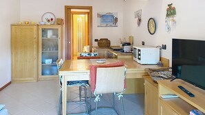 Een kleine keuken met een eethoek, een televisie en een houten kast.
