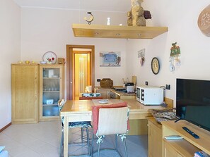 A compact kitchen with a dining area, a TV, and a wooden cabinet. - Coniglio Beach by Interhome (Villasimius)
