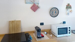 Een keuken met een magnetron, broodrooster en een houten snijplank.
