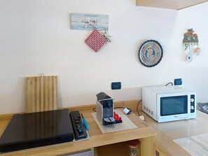 A kitchen with a microwave, toaster, and wooden cutting board. - Coniglio Beach by Interhome (Villasimius)