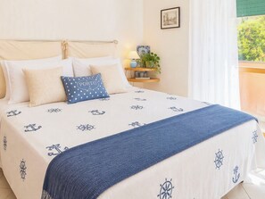 A bed with a nautical-themed bedspread, a blue polka-dotted pillow, and a blue throw blanket. - Coniglio Beach by Interhome (Villasimius)