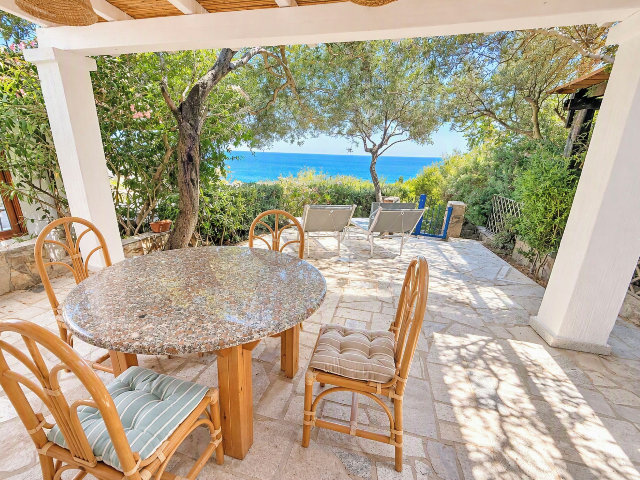 Une terrasse extérieure avec une table ronde et des chaises, donnant sur une étendue d’eau.