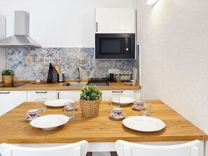 A modern kitchen with white cabinets, a black microwave, and a tiled backsplash. - Porto Luna 1 by Interhome (Villasimius)
