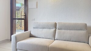 Un canapé beige dans une pièce dont le mur est texturé et qui possède une fenêtre.