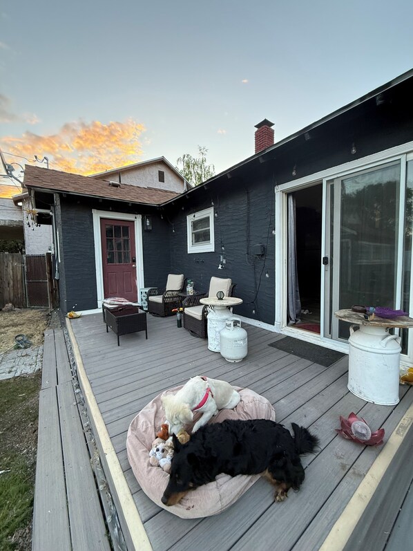 A deck with outdoor furniture, a dog bed, and a large white propane tank.