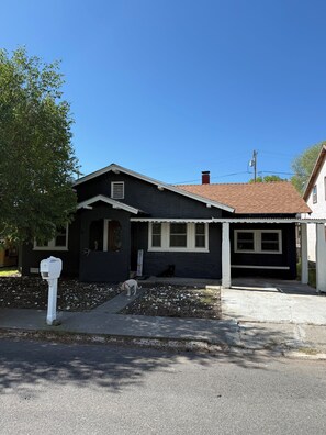 A two-story house with a dark exterior, a front porch, and a mailbox.