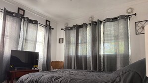 A bedroom with a bed, a TV, a chair, and curtains. - Fantastic 4-bedroom house in quaint Alturas for your getaway Centrally located!! (Alturas)