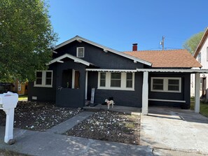 A residential house with a front porch, a mailbox, and a dog standing outside.