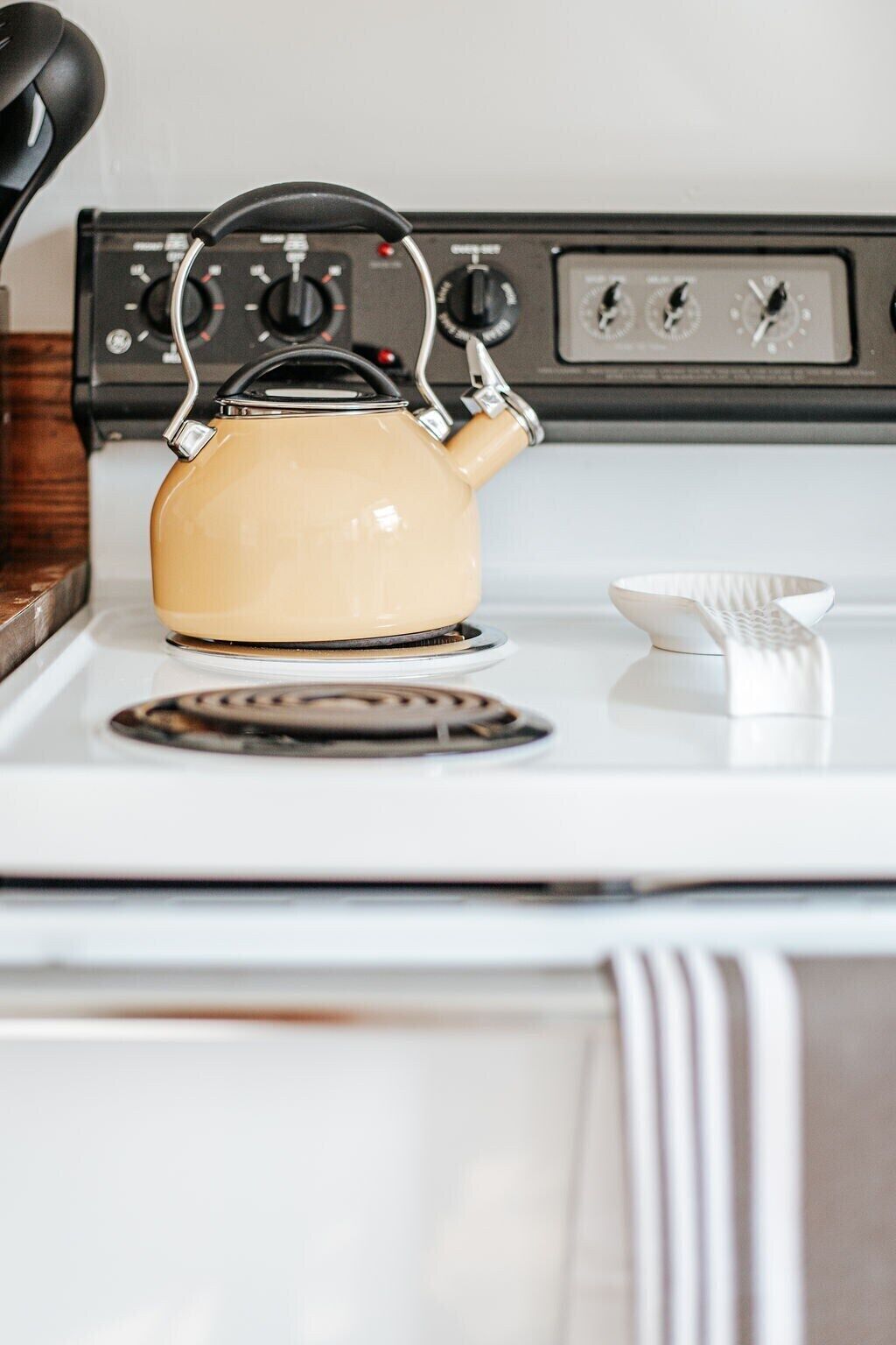 Una cocina con estufa, hervidor y un cuenco blanco.
