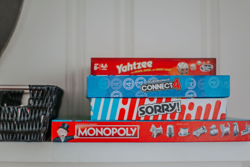 A stack of board games including Monopoly, Yahtzee, Connect4, and Sorry!