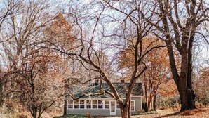 Une maison entourée d’arbres, sous un ciel dégagé.