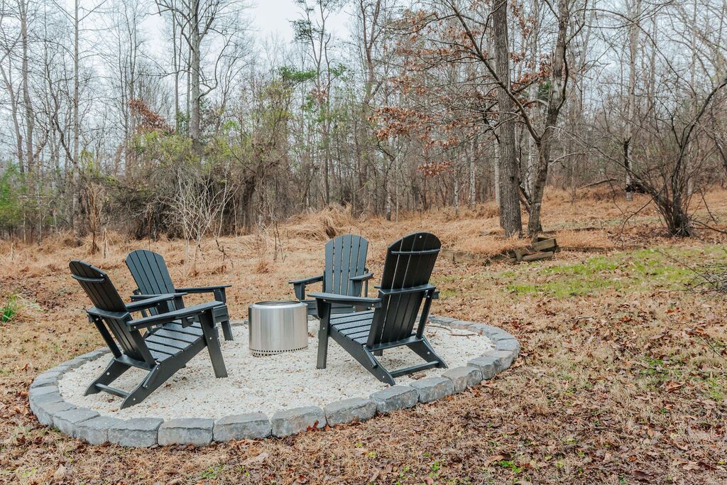 A circular seating area with three Adirondack chairs and a metal table, surrounded by a stone border.