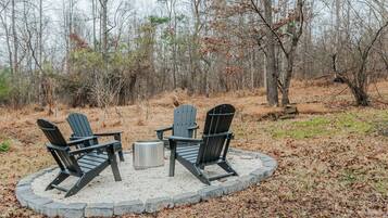A circular seating area with three Adirondack chairs and a metal table, surrounded by a stone border.