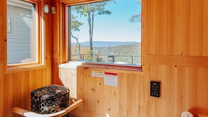 A cabin with a wooden interior, a window with a view of trees and hills, a clock, and a warning sign. - Art & Soul Main House (Nellysford)