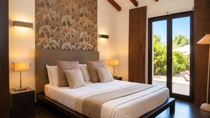 A modern bedroom with a large bed, two bedside lamps, a patterned wall, and a view through a glass door. - Villa with top-of-the-range amenities Swimming pool and fitness room (San-Gavino-di-Carbini)