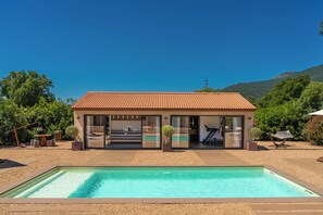 A modern villa with a swimming pool, outdoor seating, and a mountain backdrop. - Villa with top-of-the-range amenities Swimming pool and fitness room (San-Gavino-di-Carbini)