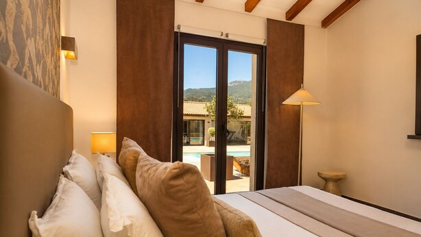 A bedroom with a bed, pillows, a nightstand, a lamp, and a view of a pool and mountains. - Villa with top-of-the-range amenities Swimming pool and fitness room (San-Gavino-di-Carbini)