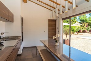 Eine moderne Küche mit Backofen, ein Essbereich mit einer Bank und Blick auf eine Außenpatio mit Sonnenschirmen.