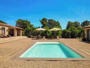 A rectangular swimming pool with a clear blue water, surrounded by a pebble ground, with two umbrellas and lounge chairs. - Villa with top-of-the-range amenities Swimming pool and fitness room (San-Gavino-di-Carbini)