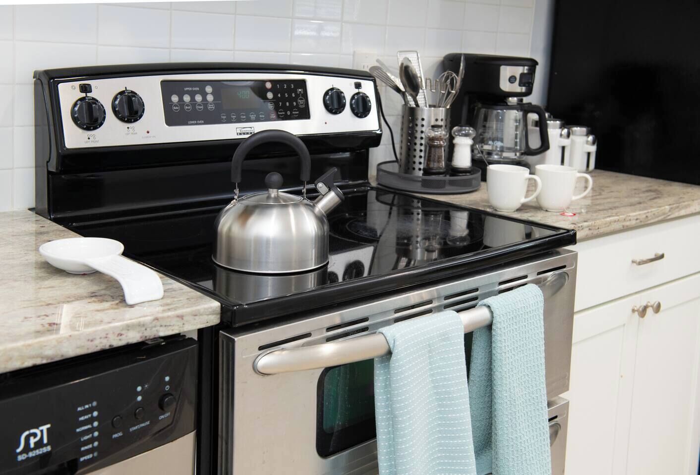 A kitchen with a stove, oven, coffee maker, and utensils.