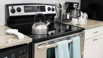 A kitchen with a stove, oven, coffee maker, and utensils.