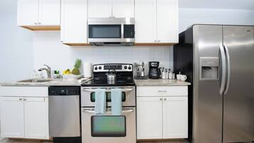 A modern kitchen with white cabinets, stainless steel appliances, and a built-in dishwasher.