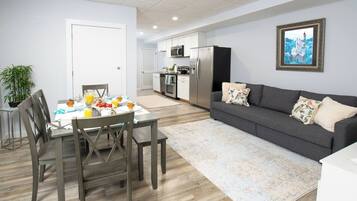 A modern kitchen with a refrigerator, microwave, and stove. There is a dining area with a table set for breakfast.