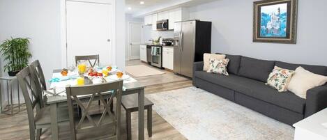 Una cocina moderna con refrigerador, microondas y estufa. Hay un comedor con una mesa lista para el desayuno.