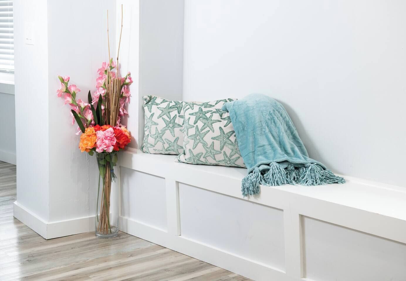 A white bench with a star-patterned pillow and a blue throw blanket.