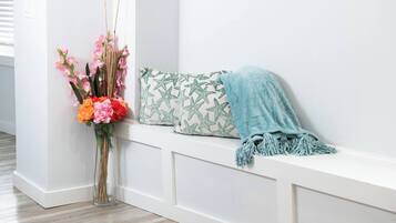 A white bench with a star-patterned pillow and a blue throw blanket.