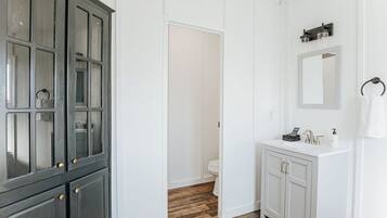 Un baño con tocador blanco, un espejo y un armario.