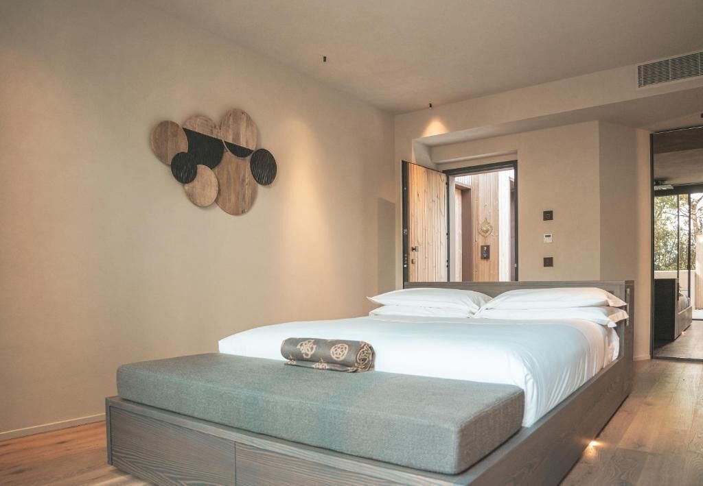 Une chambre moderne avec un lit, un banc et un élément décoratif fixé au mur.