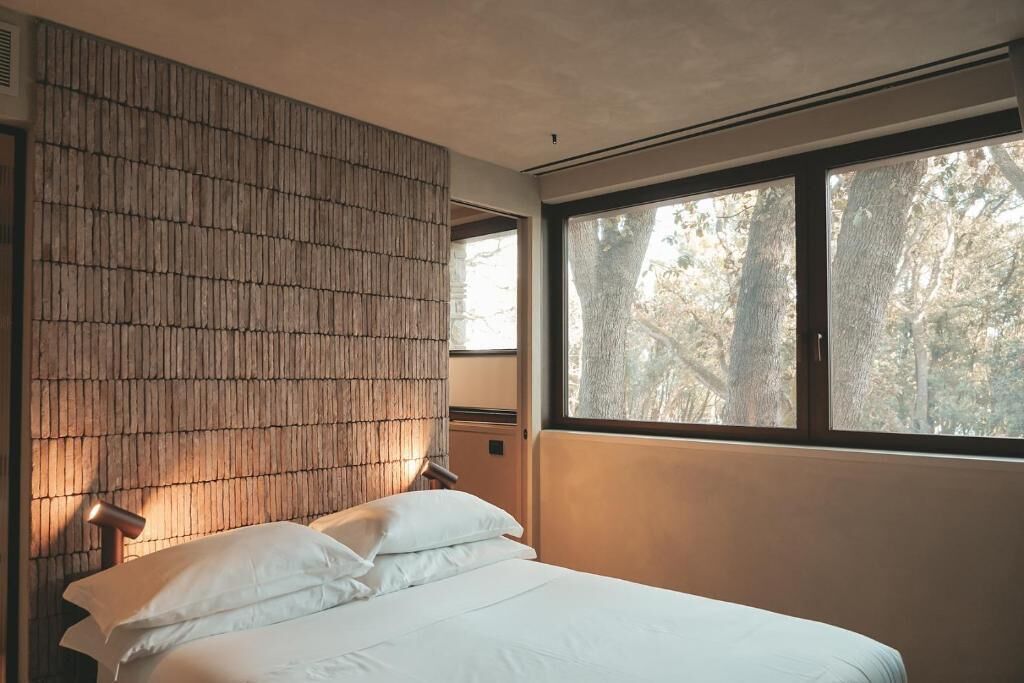 A bedroom with a bed, a window, and a wall with vertical lines.
