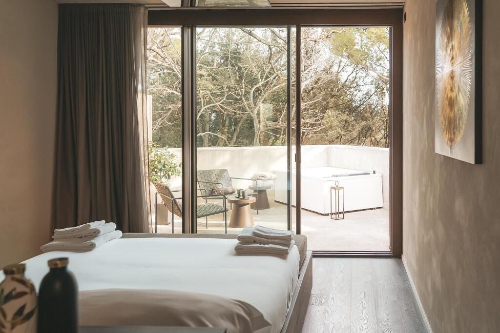 Une chambre d’hôtel avec un grand lit, une vue sur l’espace extérieur et une porte-fenêtre coulissante.