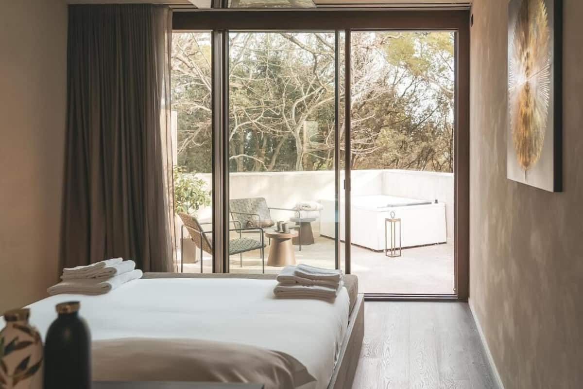 A hotel room with a large bed, a view of the outdoor area, and a sliding glass door.