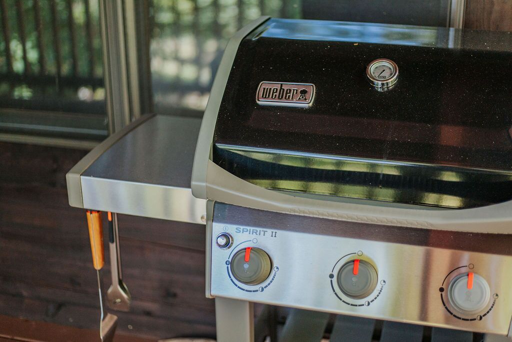 A Weber Spirit II grill with two control knobs and a temperature gauge.