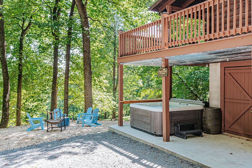 A hot tub under a wooden deck with a view of a forest.