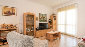 Ein Wohnzimmer mit Holzschrank, Fernseher, kleinem Tisch und einer Couch.