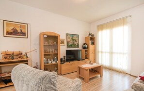 Ein Wohnzimmer mit Holzschrank, Fernseher, kleinem Tisch und einer Couch.