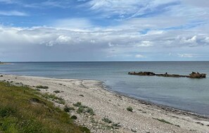 A coastal landscape with a pebbly beach, calm sea, and overcast sky. - Stunning home in Sjællands Odde with WiFi (Sjællands Odde)