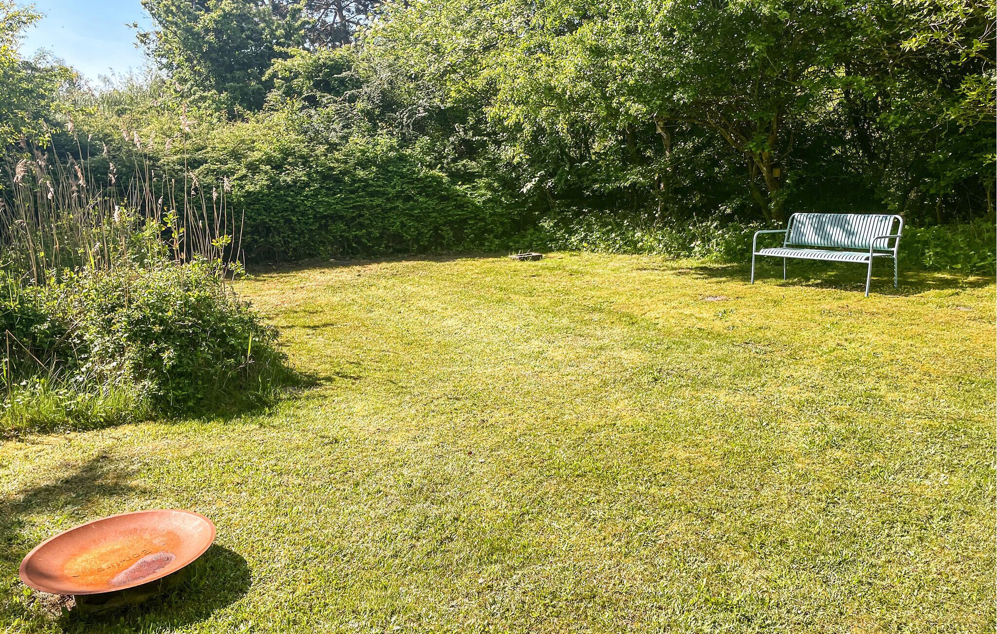 A grassy outdoor area with a metal bench and a red object on the ground.