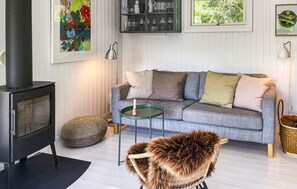 A living room with a sofa, a small table, a decorative chair, a fireplace, and wall art. - Stunning home in Sjællands Odde with WiFi (Sjællands Odde)