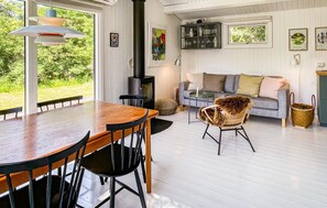 A cozy living room with a fireplace, a sofa, and a dining area with chairs. - Stunning home in Sjællands Odde with WiFi (Sjællands Odde)