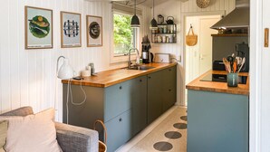 Una cocina compacta con encimera de madera, pileta integrada y comedor con sofá y mesa de centro.